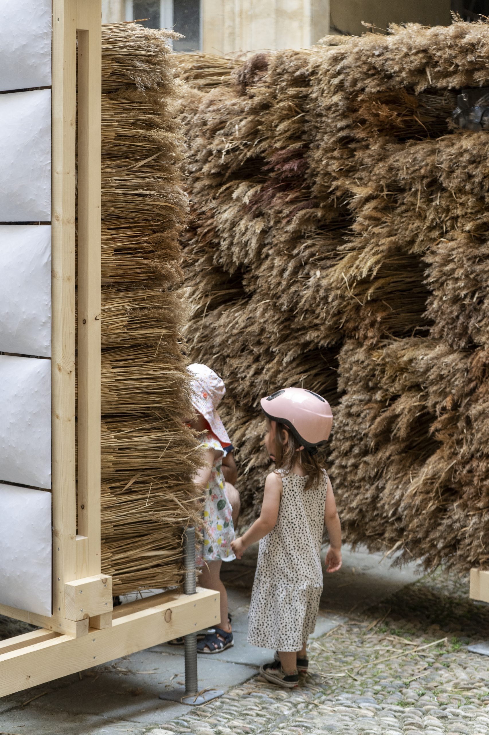 Child touching the reed sheaves inside the installation