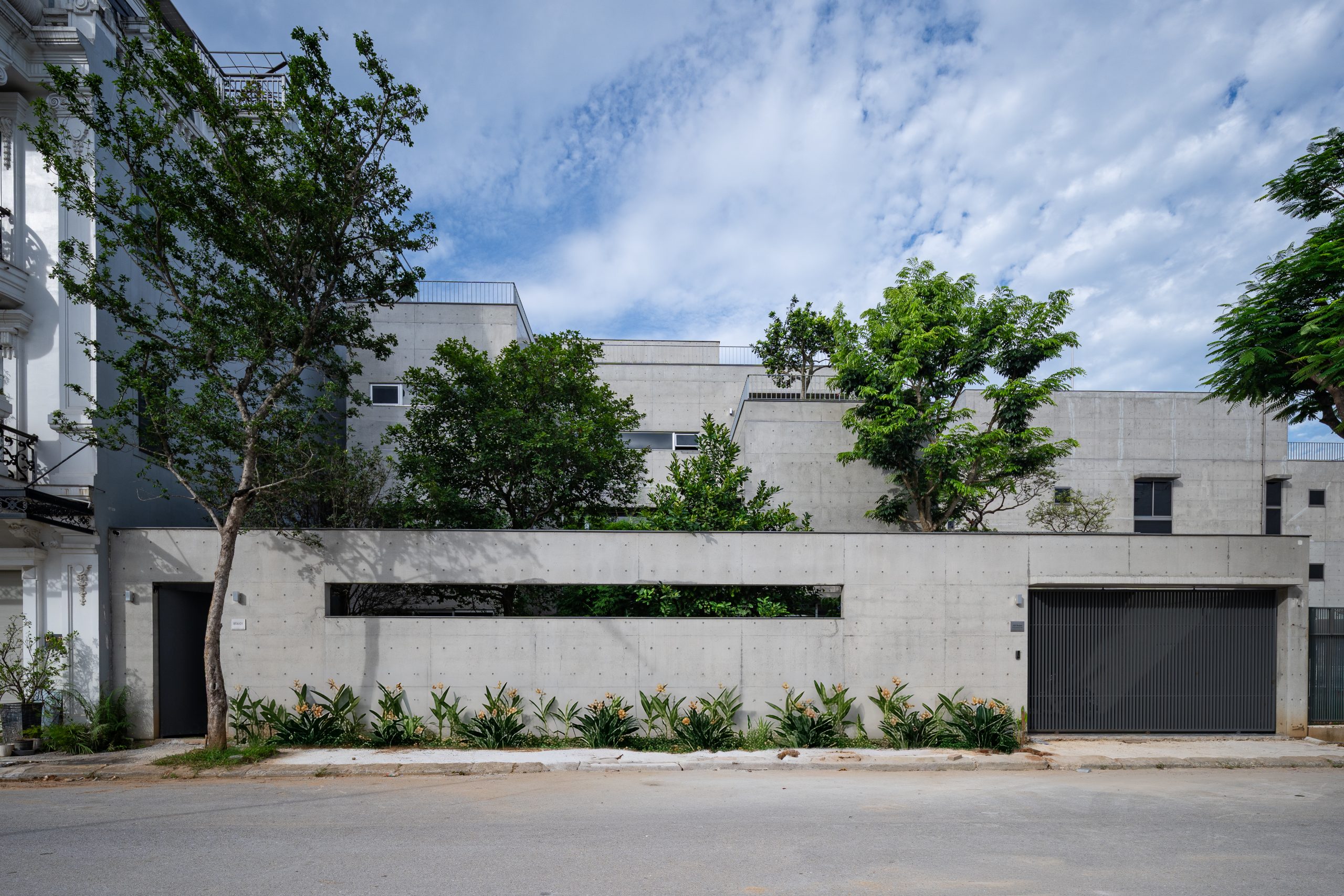 Street elevation with concrete walls and planted terraces, House K by HGAA
