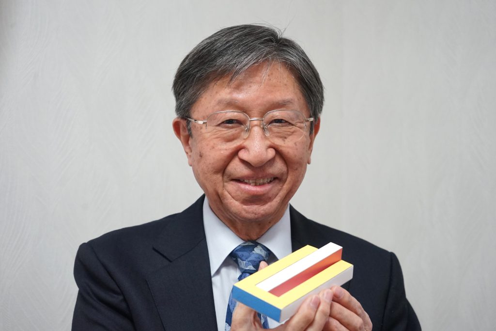 Kokichi Sugihara holding a three-dimensional illusion model