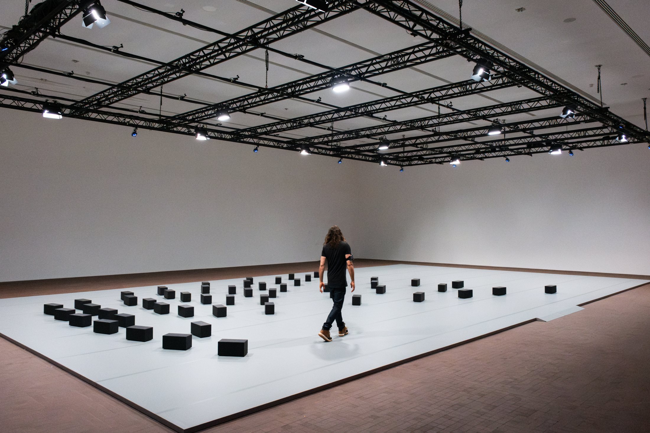 Visitor walking among DRIFT’s moving rectangular blocks at LUMA Arles