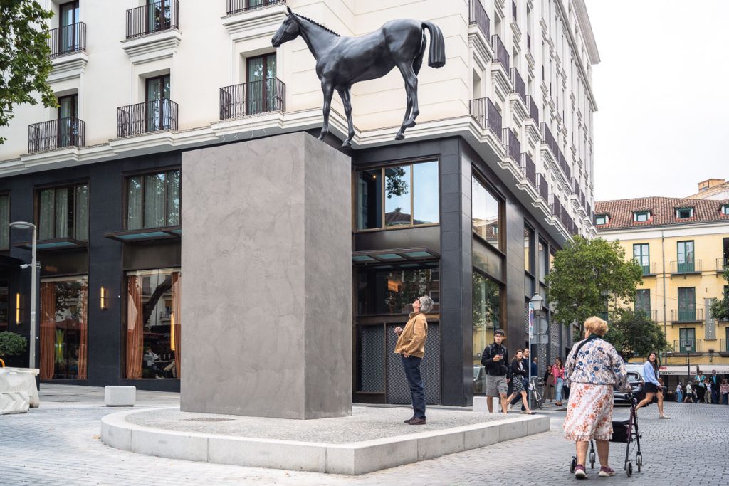 Gonzalo Lebrija’s bronze horse sculpture above Plaza del Carmen with pedestrians in Madrid