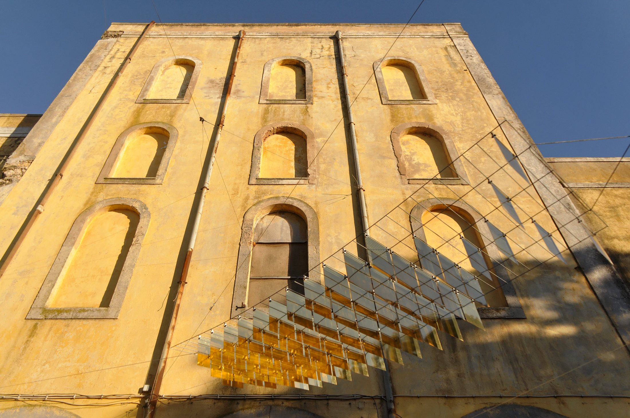 A suspended fish beside the ochre facade of Faro's former beer factory