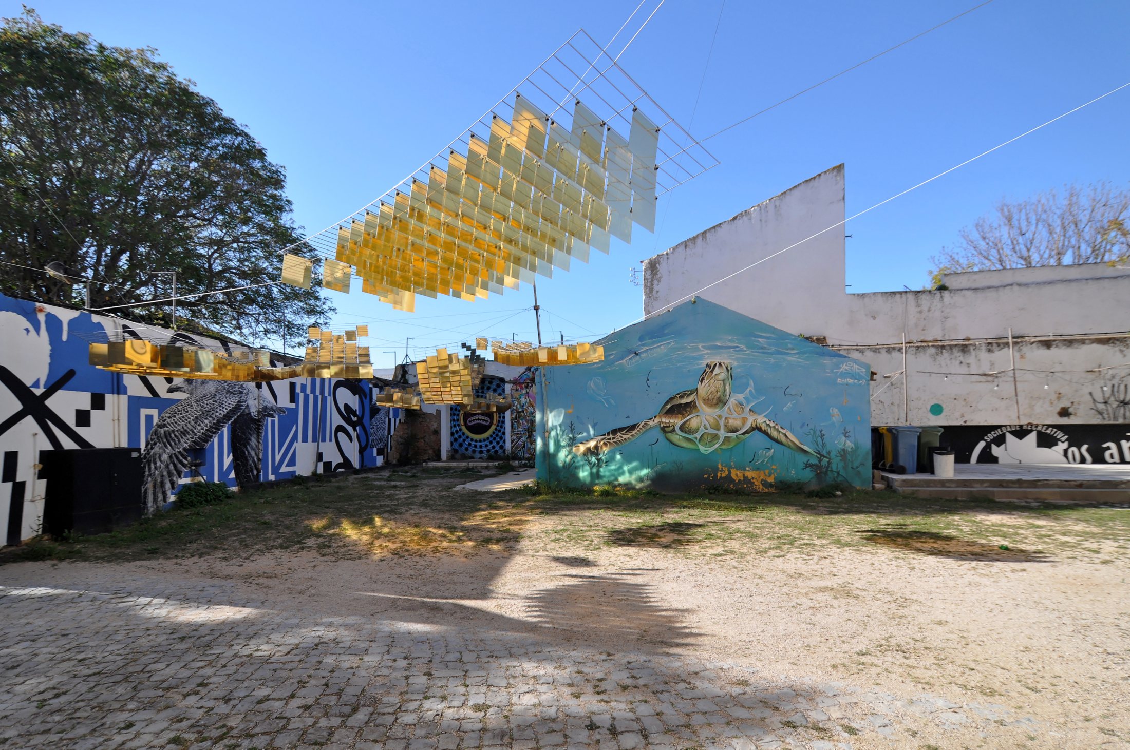 Golden mirrored fish suspended above the mural-lined courtyard at Mar Motto