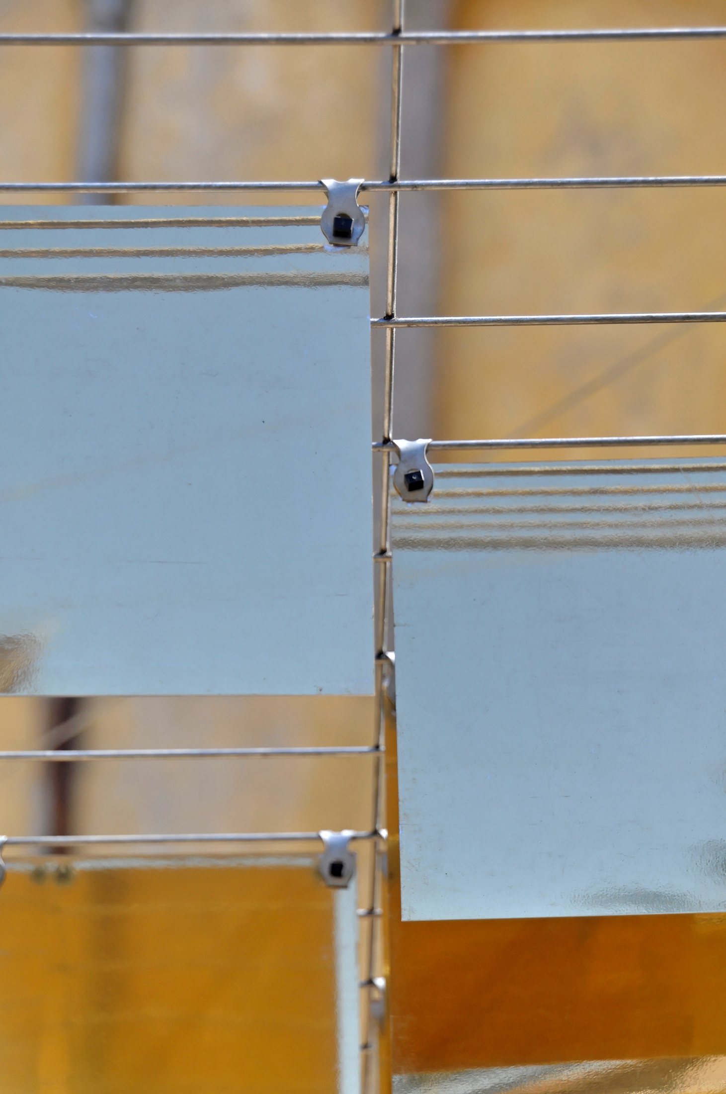 Close-up of mirrored panels and their connections to horizontal supporting wires