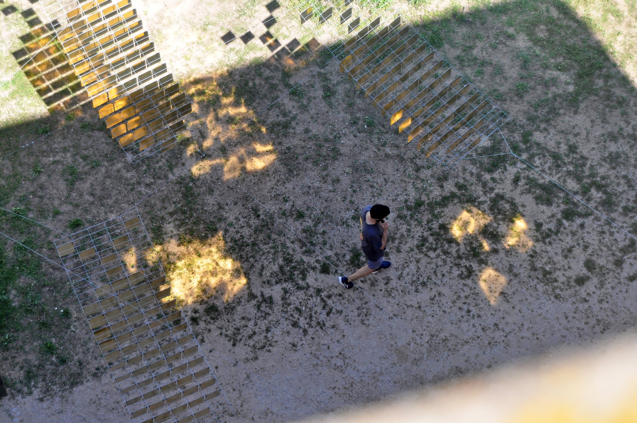 A visitor crossing the courtyard beneath scattered golden reflections