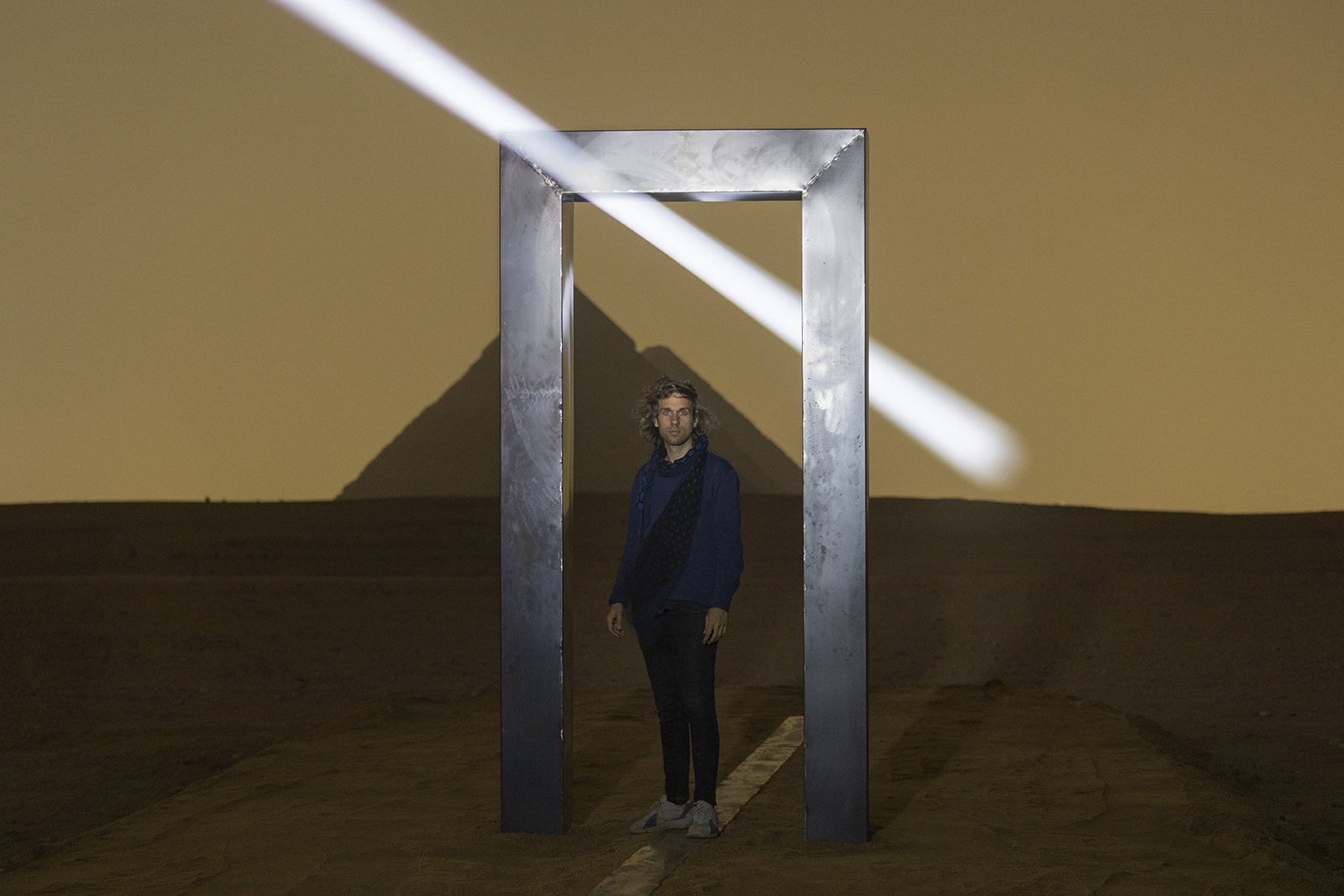 Portal of Light by Emilio Ferro, with a figure standing within the metal portal at Giza