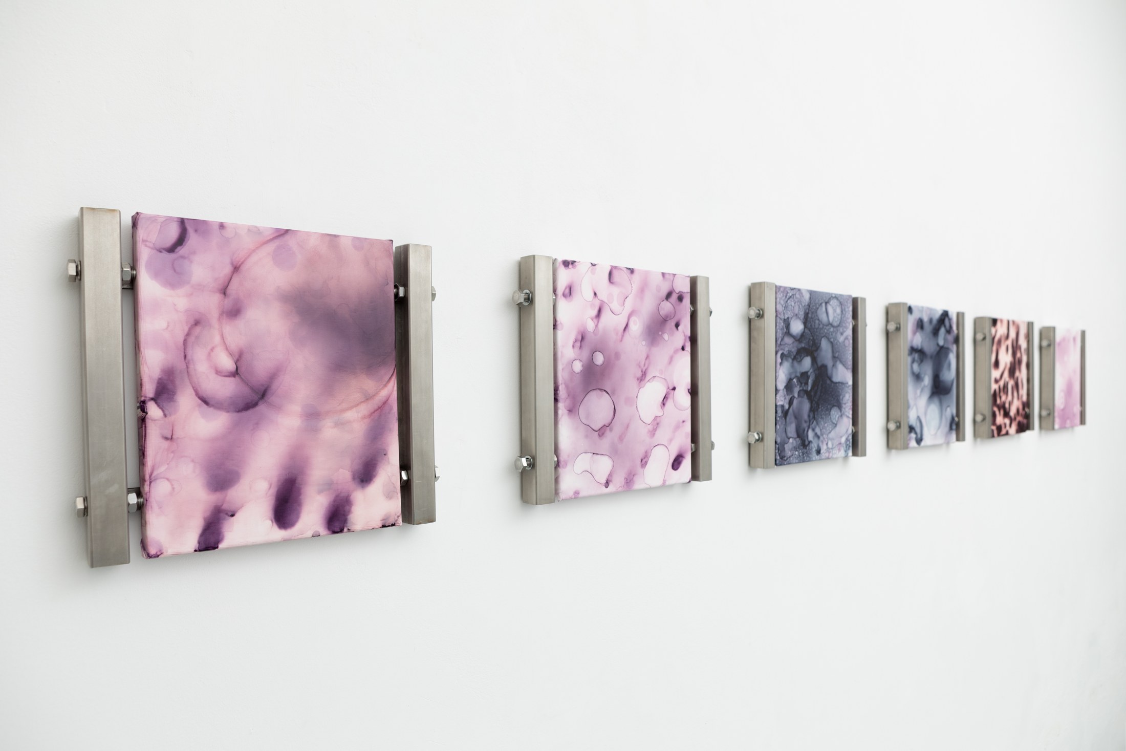 Oblique view of pink and blue works in metal mounts