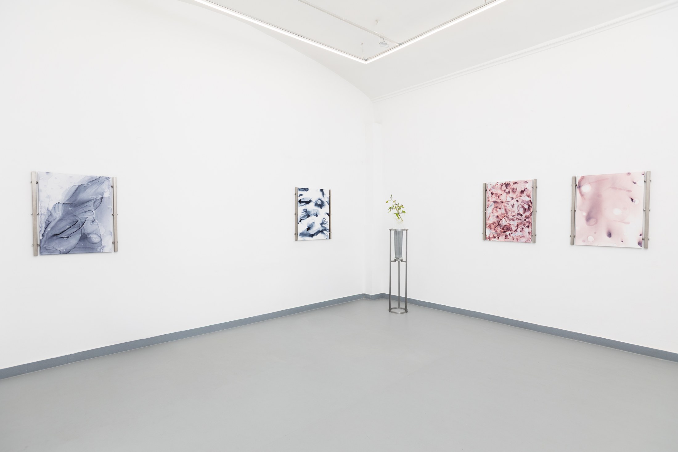 Small paintings and a plant vessel across two gallery walls