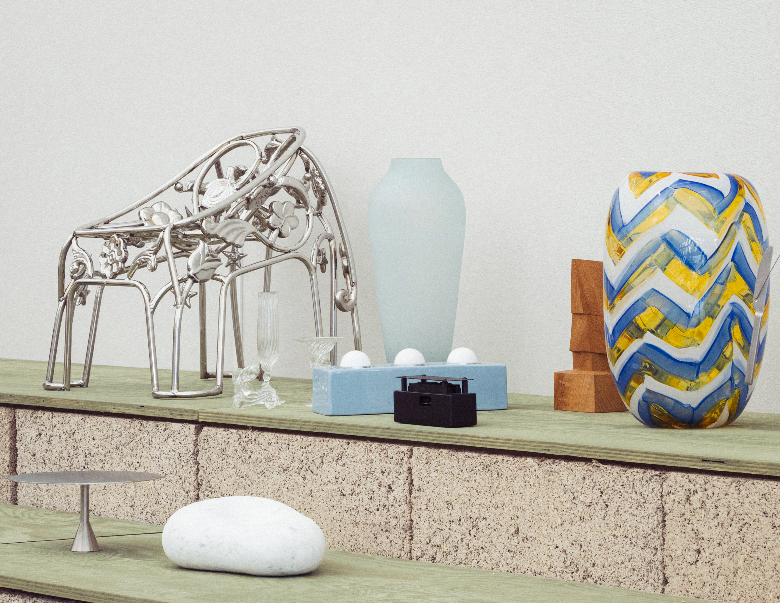 Objects displayed on green shelves supported by exposed hemp blocks