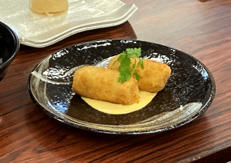 木製テーブルの上に置かれた皿の上の食べ物 自動的に生成された説明