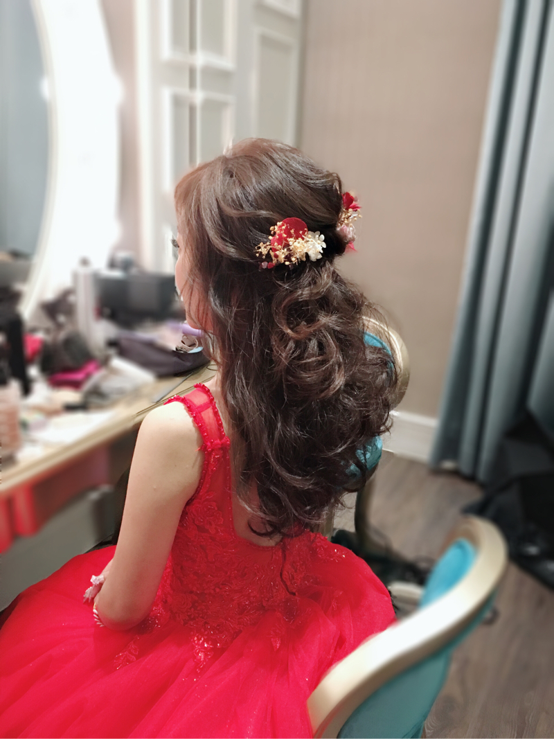 這張「新娘」的照片是一個穿著紅色禮服的女生，她頭髮上戴著紅色和金色花飾。