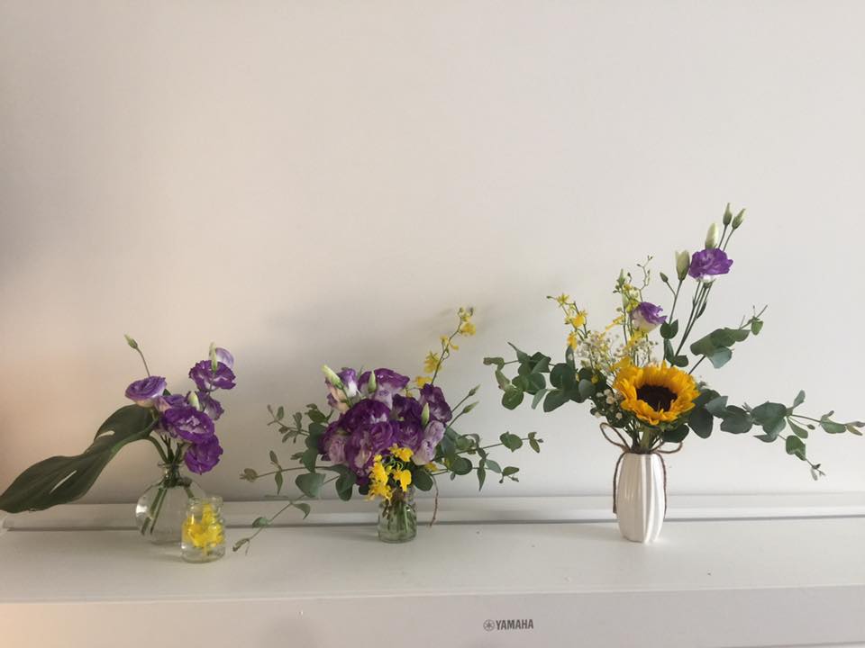 1) 照片顯示了三個花瓶中的花朵，其中兩個花瓶中裝的是紫色的花，另一個花瓶中裝的是向日葵