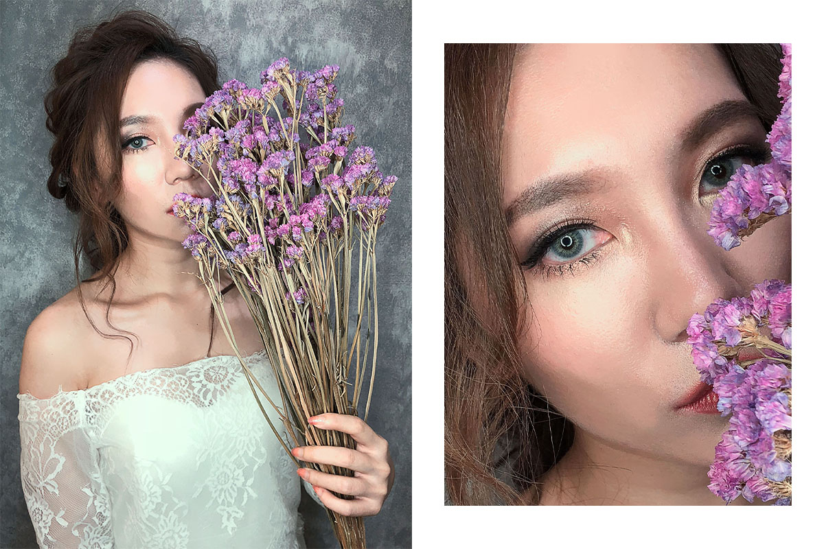 1) 照片中是一位女性，她穿著白色蕾絲禮服，手裡拿著一束乾燥的紫花，並用花遮住部分臉