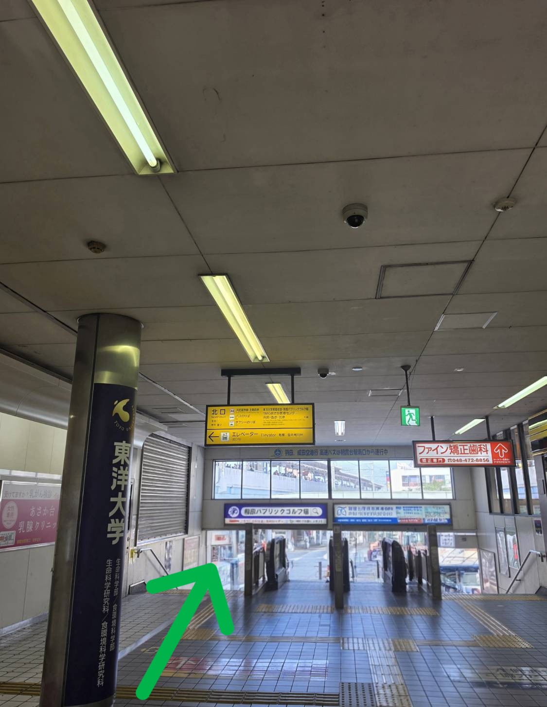 「北口」と書かれた黄色い案内看板の下を通り、階段またはエスカレーターを使って降ります。