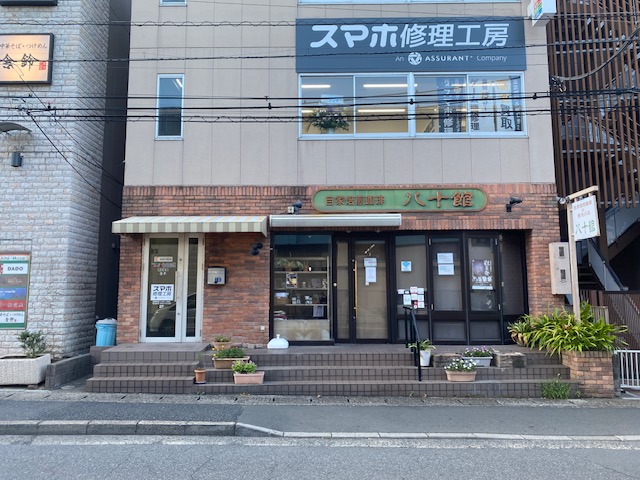 右に進むとすぐに喫茶店が見えてきます。【自家焙煎珈琲　八十館】が目印です。こちらの2階に店舗があります。