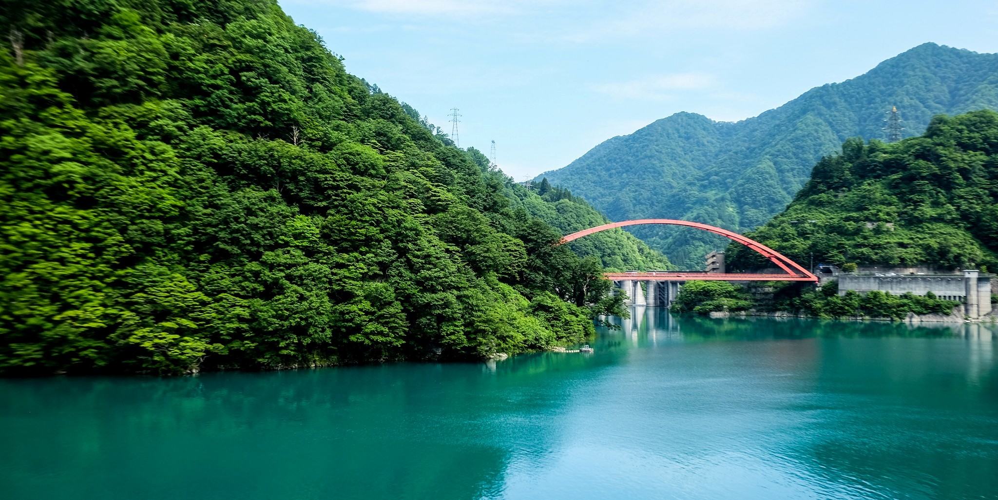 The green color of the mountains and forests blends with the emerald green color of Lake Kurobe at Unazuki Dam