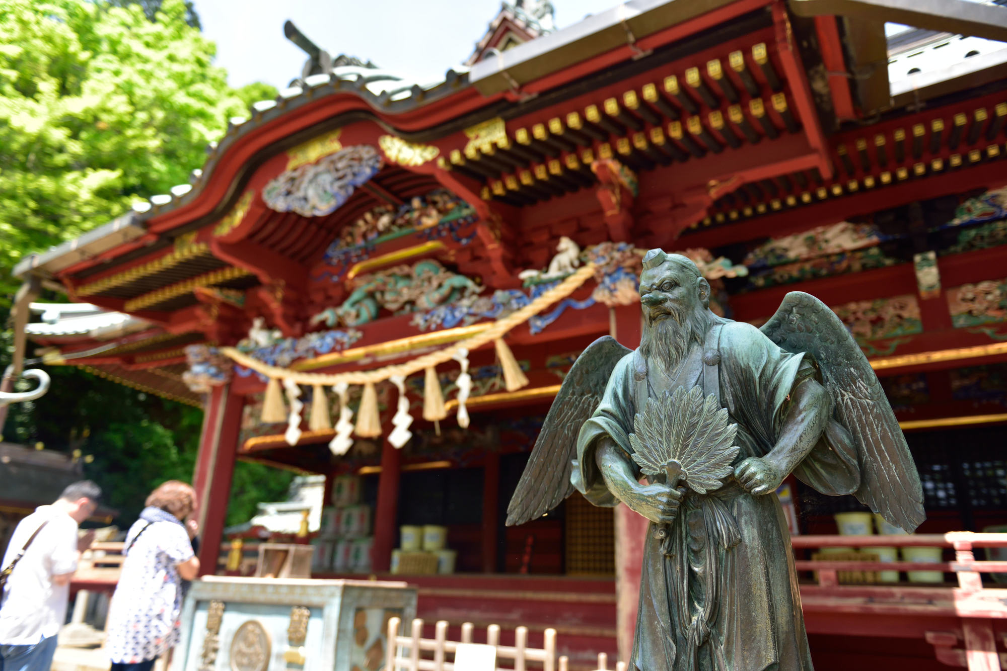 A Tengu statue, the guardian of mountains and forests, stands out with its long nose, wings, and a fan in its hand