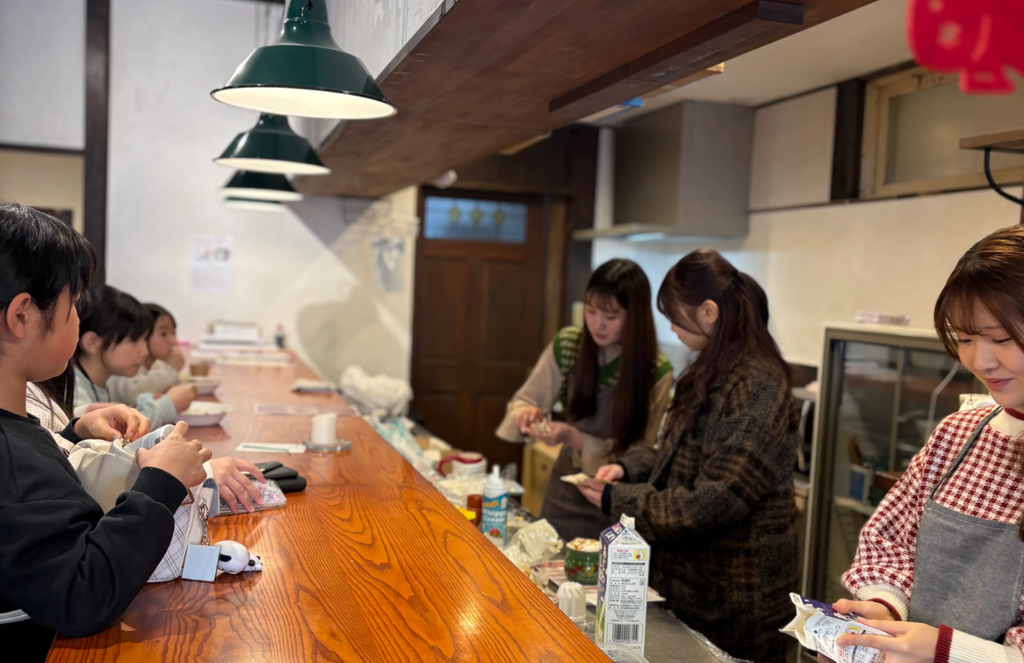 飲み物を作る大学生とそれを見るこどもたち