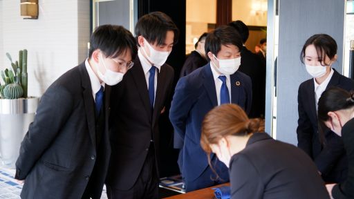 オリジナルのネクタイとボールペンを受付で配布する様子