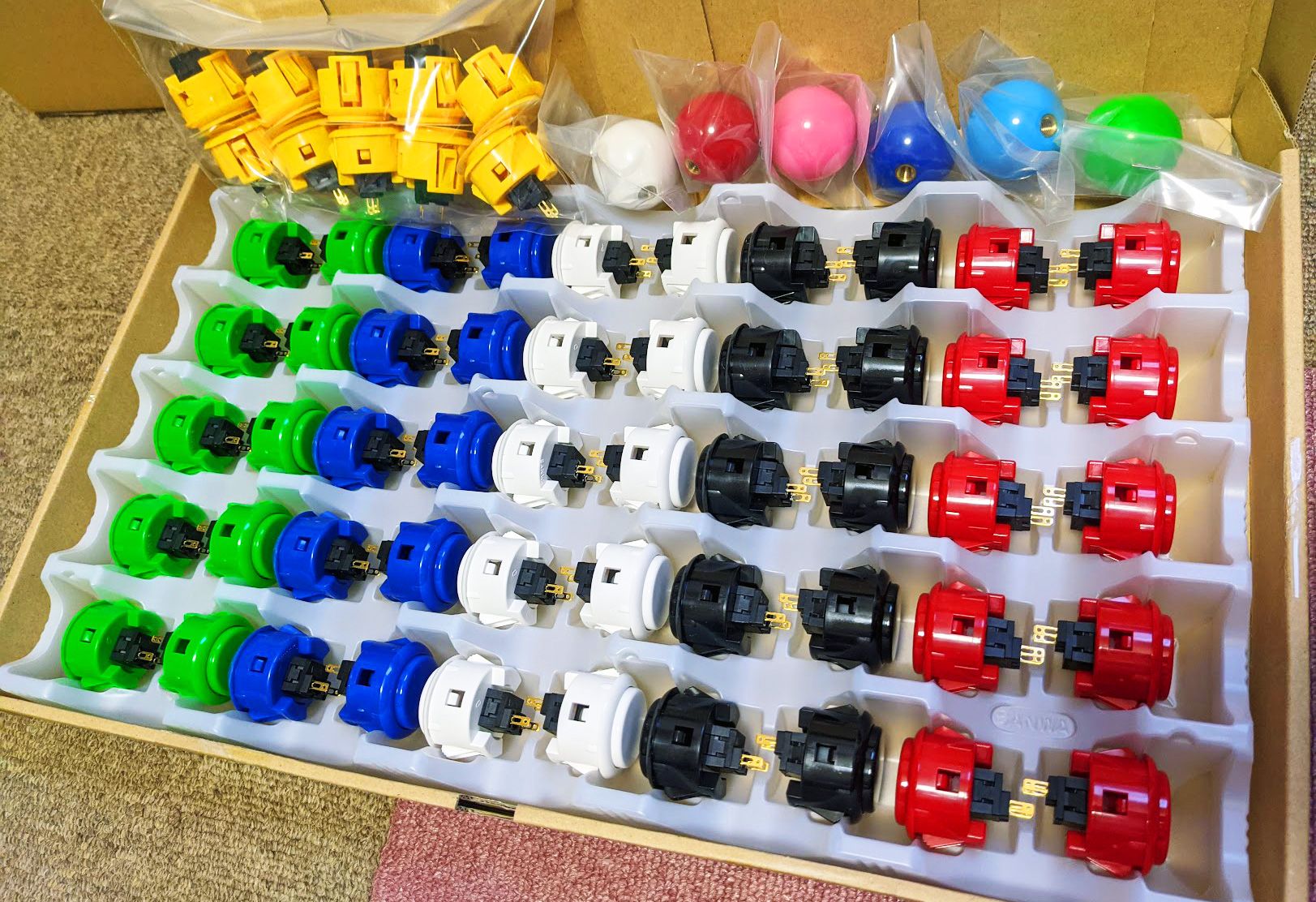 これはアケコンに使うボタンを大量購入したときの写真。こんなにたくさん買ったのは初めてだったので、専用の仕切りに入って届いたときはびっくりしました。デザインは難しくても、好みのカラーするだけなら簡単ですよ！